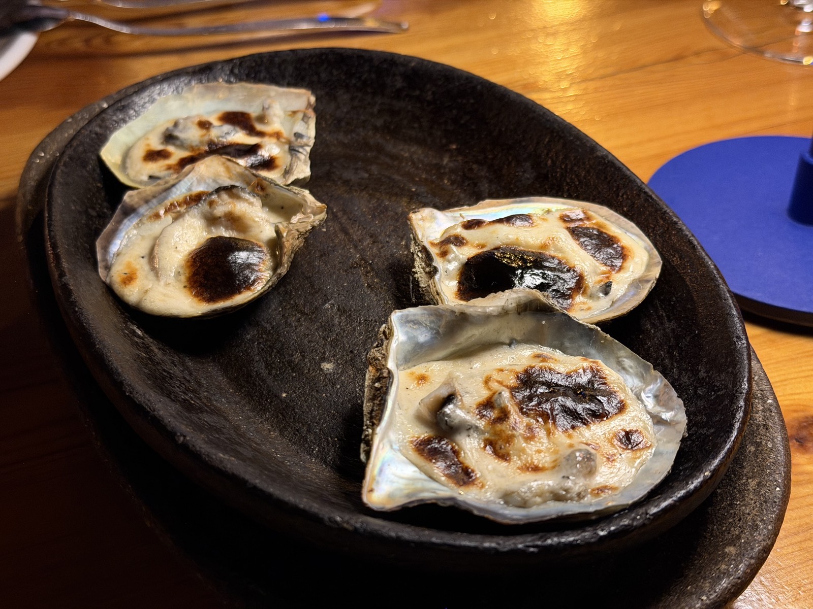 Huîtres gratinées servies dans leur coquille sur un plat de pierre noire chez Orfoz Bodrum
