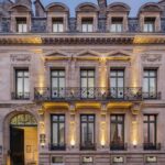 Façade éclairée de l'hôtel particulier du Palais Gallien à Bordeaux, avec balcon en fer forgé et porte cintrée