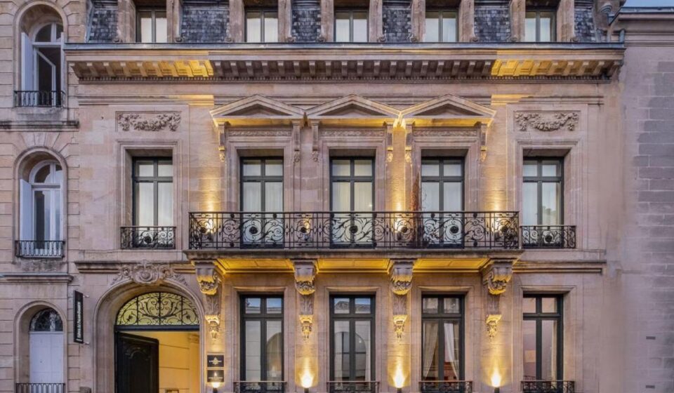 Façade éclairée de l'hôtel particulier du Palais Gallien à Bordeaux, avec balcon en fer forgé et porte cintrée