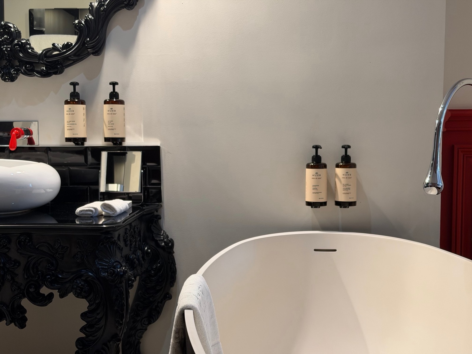 Distributeurs muraux Nuxe Rêve de miel, meuble-vasque noir et baignoire blanche du Palais Gallien à Bordeaux